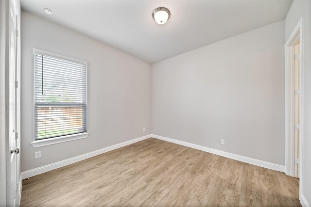 spare room with baseboards and light wood-style flooring