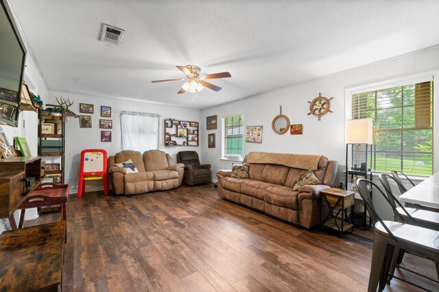 living room featuring ceiling fan, visible vents, and dark wood finished floors