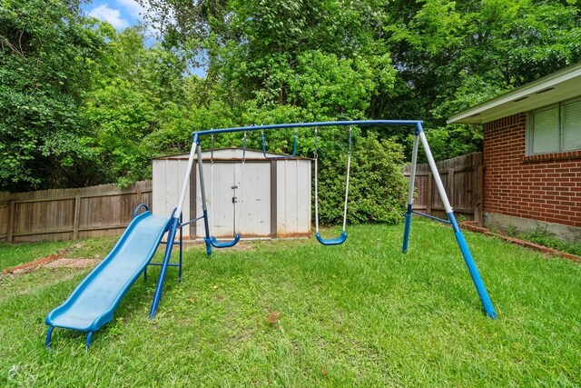 view of jungle gym with a fenced backyard, an outbuilding, a yard, and a shed