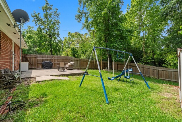 view of playground featuring a lawn, a fenced backyard, and a patio area