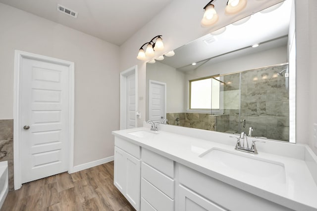 full bathroom featuring a sink, a shower stall, double vanity, and wood finished floors