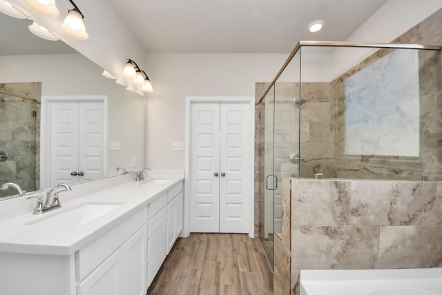 bathroom with a sink, a bath, a stall shower, and double vanity