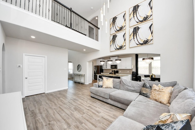living area featuring arched walkways, plenty of natural light, and a towering ceiling