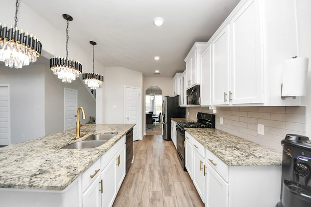 kitchen with a sink, a chandelier, white cabinetry, backsplash, and black appliances