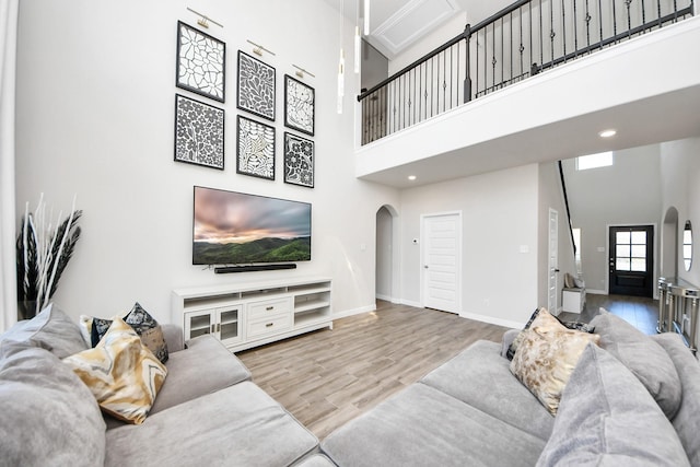 living area featuring baseboards, arched walkways, a high ceiling, and wood finished floors