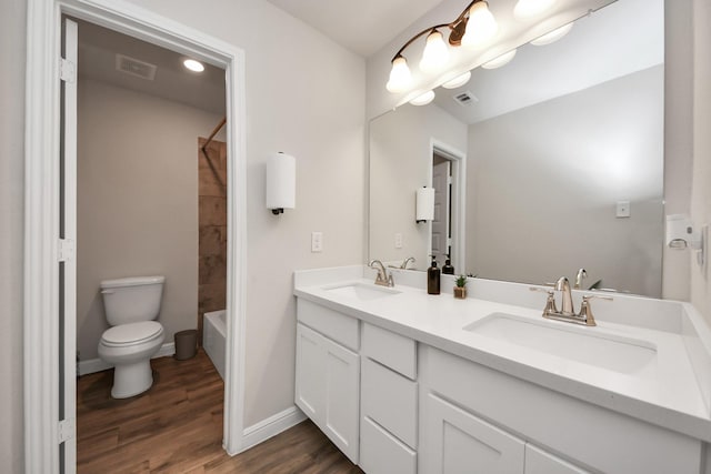 full bathroom with toilet, visible vents, a sink, and wood finished floors