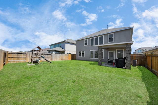 back of house with a yard, a fenced backyard, and a playground