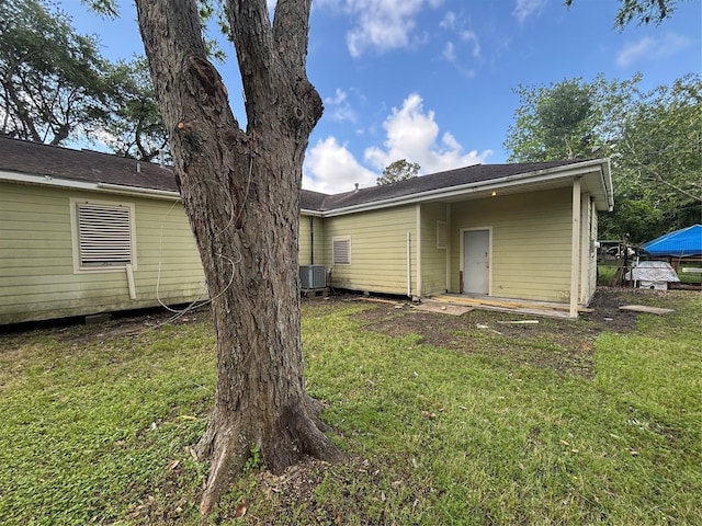 rear view of property with a yard and central AC