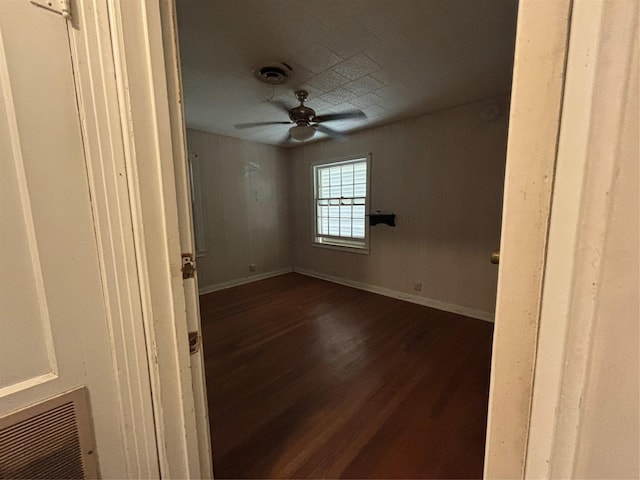 empty room with ceiling fan, dark wood finished floors, baseboards, and visible vents