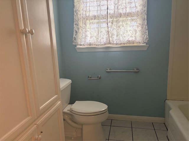 full bathroom with a tub to relax in, baseboards, tile patterned floors, and toilet