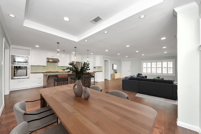 dining room featuring visible vents, ornamental molding, recessed lighting, a tray ceiling, and dark wood finished floors
