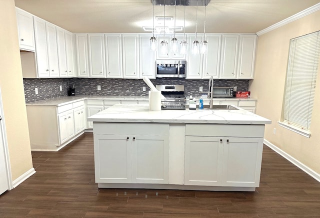 7130 Liberty Oak Ct, Houston, TX 77049 - kitchen with appliances with stainless steel finishes, a kitchen island with sink, baseboards, white cabinets, and tasteful backsplash