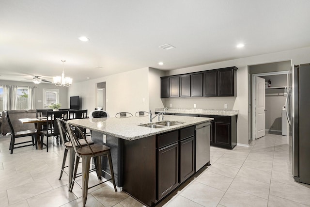 23706 Bluewood Trce, Tomball, TX 77375 - kitchen featuring appliances with stainless steel finishes, a sink, an island with sink, light stone countertops, and a chandelier