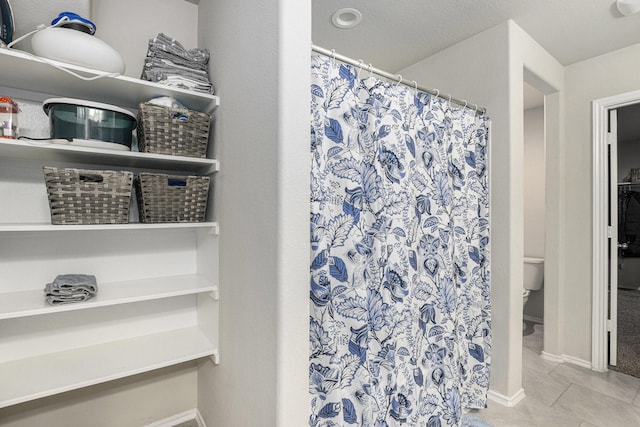 23706 Bluewood Trce, Tomball, TX 77375 - bathroom with tile patterned floors, toilet, a shower with shower curtain, and baseboards