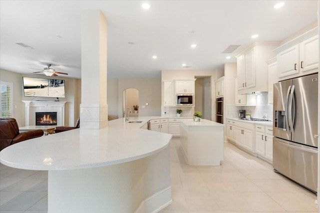 kitchen featuring ceiling fan, a sink, light tile patterned floors, open floor plan, and stainless steel appliances