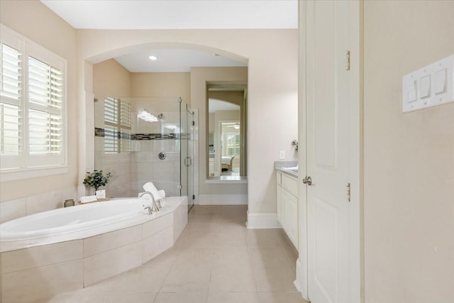 bathroom with vanity, tile patterned floors, baseboards, a bath, and a stall shower