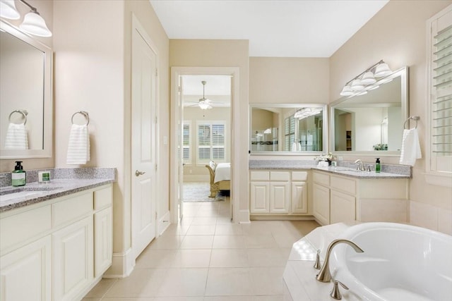 ensuite bathroom featuring a ceiling fan, a garden tub, two vanities, a sink, and tile patterned floors
