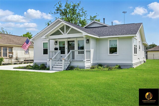 view of front facade with roof with shingles, cooling unit, a porch, and a front lawn