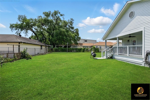 view of yard with ceiling fan, fence, and covered porch