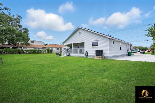 rear view of house with a ceiling fan, a yard, covered porch, and central AC unit