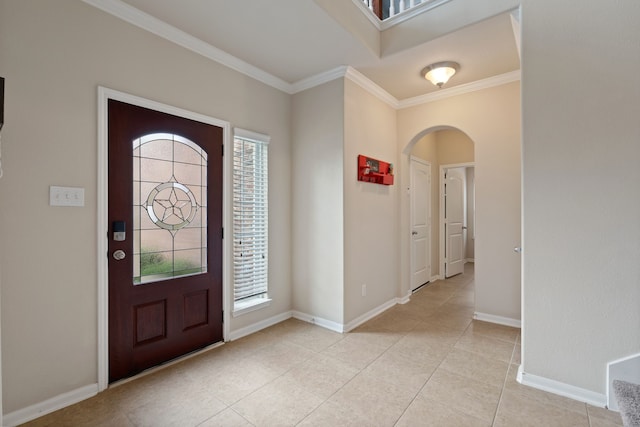 foyer entrance featuring baseboards, arched walkways, light tile patterned floors, and ornamental molding