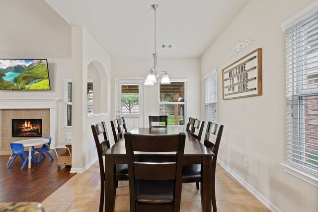 dining space with a healthy amount of sunlight, baseboards, a fireplace, and light tile patterned flooring