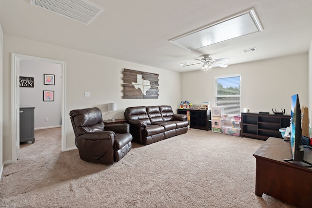 living room with ceiling fan, visible vents, carpet, and attic access