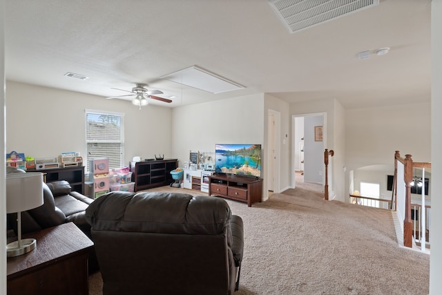 carpeted living area featuring a ceiling fan, attic access, and visible vents