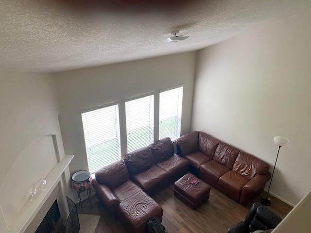 living area with a fireplace with flush hearth, a textured ceiling, and wood finished floors