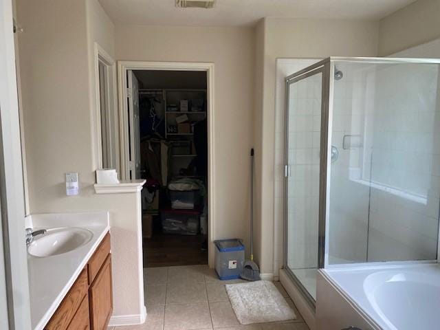 full bath with vanity, tile patterned floors, a walk in closet, and a stall shower