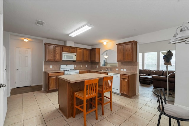 102 Pebble Walk Ln, Dickinson, TX 77539 - kitchen featuring white appliances, light countertops, light tile patterned floors, and a center island
