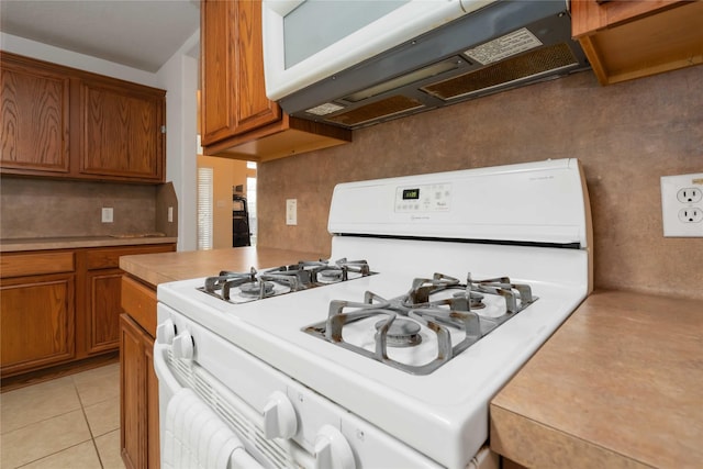 102 Pebble Walk Ln, Dickinson, TX 77539 - kitchen with white appliances, brown cabinets, light countertops, and light tile patterned flooring