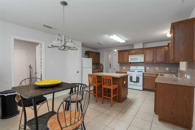 102 Pebble Walk Ln, Dickinson, TX 77539 - kitchen featuring white appliances, a sink, a kitchen island, light tile patterned floors, and light countertops
