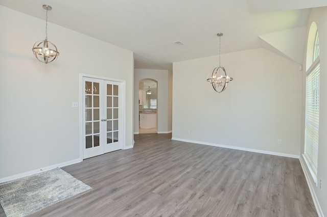unfurnished dining area with light wood-style floors, arched walkways, plenty of natural light, and a chandelier