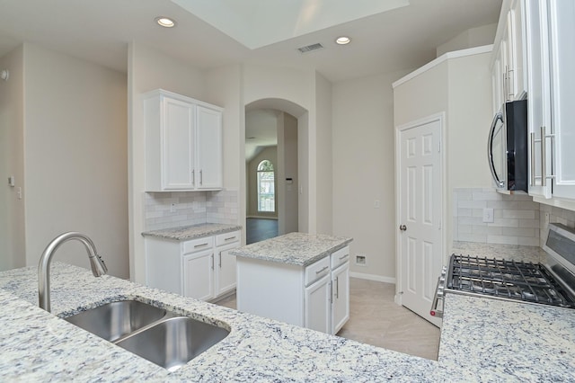 kitchen featuring decorative backsplash, visible vents, arched walkways, a sink, and recessed lighting
