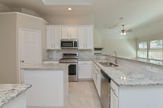 kitchen featuring decorative backsplash, a peninsula, white cabinetry, a sink, and appliances with stainless steel finishes