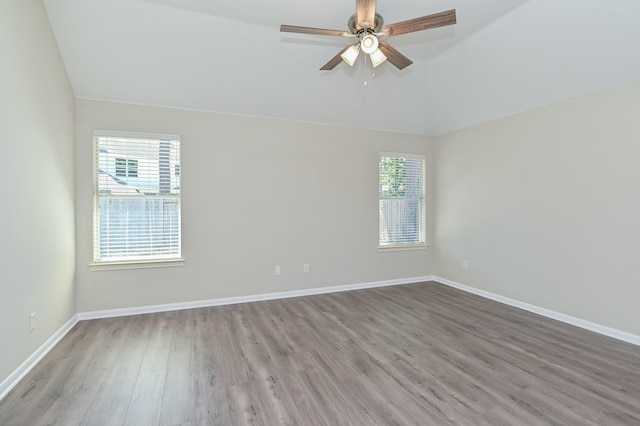 empty room featuring a ceiling fan, a wealth of natural light, lofted ceiling, and wood finished floors