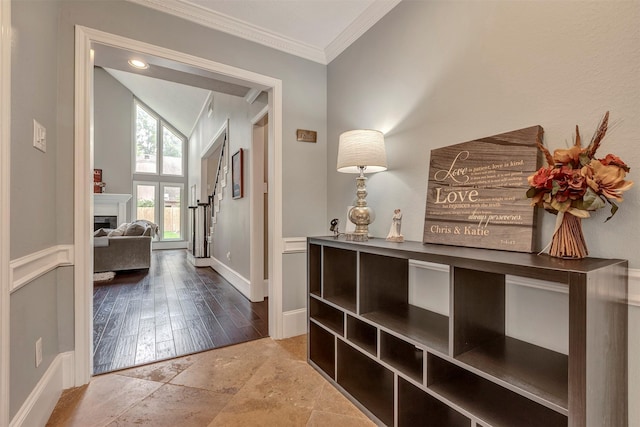 corridor featuring crown molding, stone tile floors, baseboards, and lofted ceiling