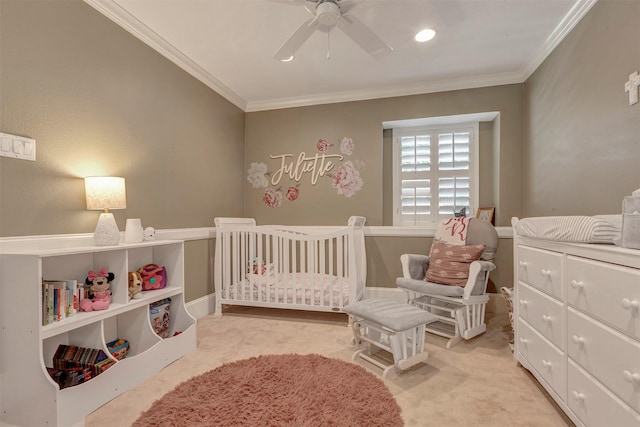 carpeted bedroom with crown molding, a nursery area, and a ceiling fan