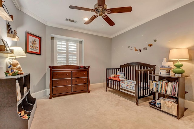 carpeted bedroom with ceiling fan, a crib, baseboards, visible vents, and ornamental molding