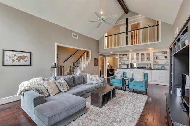 living area featuring high vaulted ceiling, dark wood finished floors, stairs, a ceiling fan, and beamed ceiling