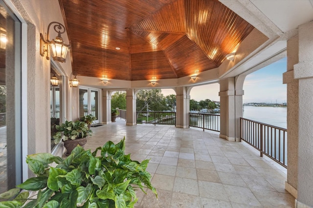 unfurnished sunroom featuring a water view, french doors, and a wealth of natural light