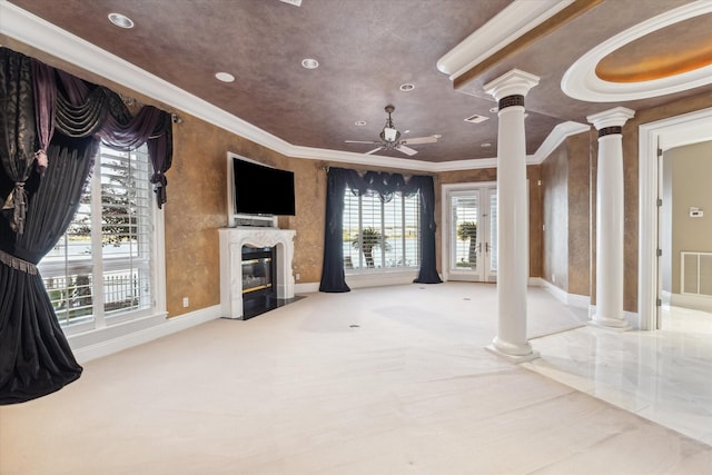 unfurnished living room with a ceiling fan, decorative columns, crown molding, baseboards, and a premium fireplace