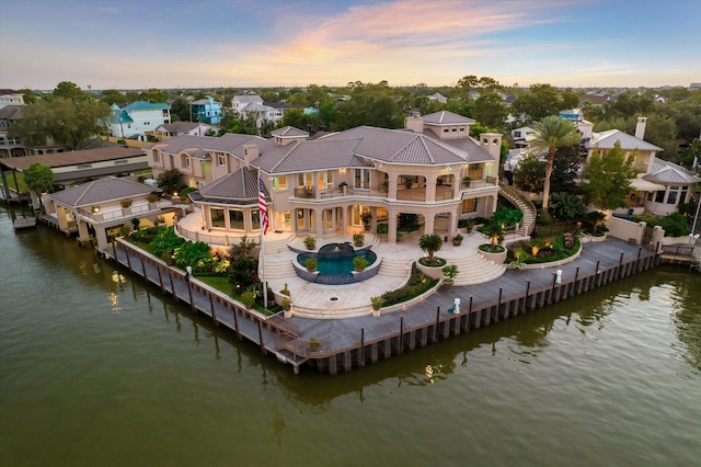 rear view of property with a water view, a chimney, a balcony, and a fenced backyard