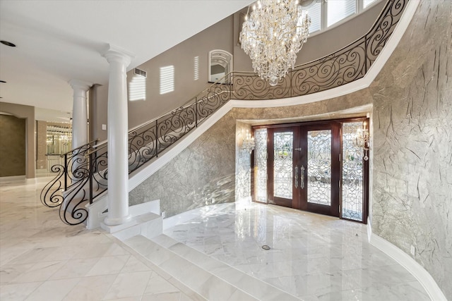 foyer entrance with a chandelier, french doors, marble finish floor, stairs, and a towering ceiling
