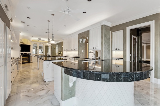 kitchen with a sink, a ceiling fan, a spacious island, and marble finish floor