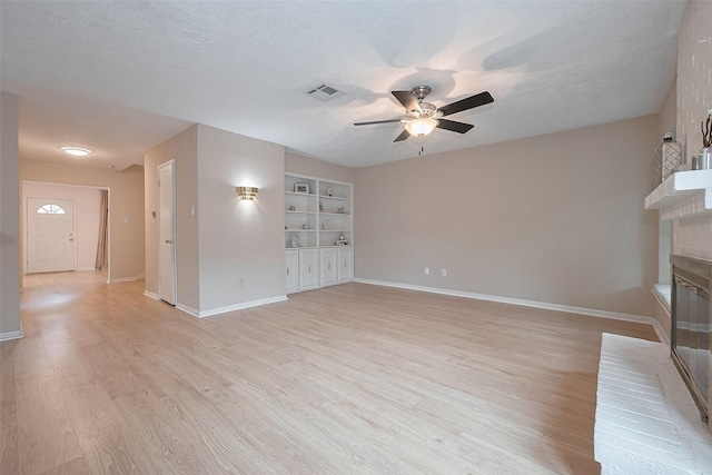 unfurnished living room featuring ceiling fan, light wood finished floors, a fireplace, baseboards, and visible vents