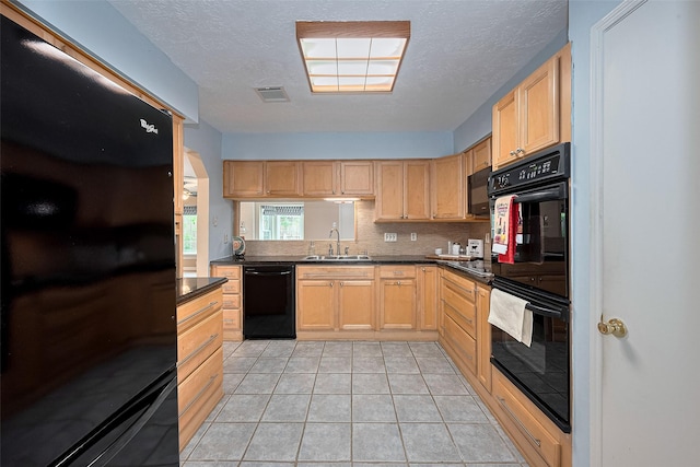 kitchen featuring visible vents, light brown cabinets, dark countertops, a sink, and black appliances