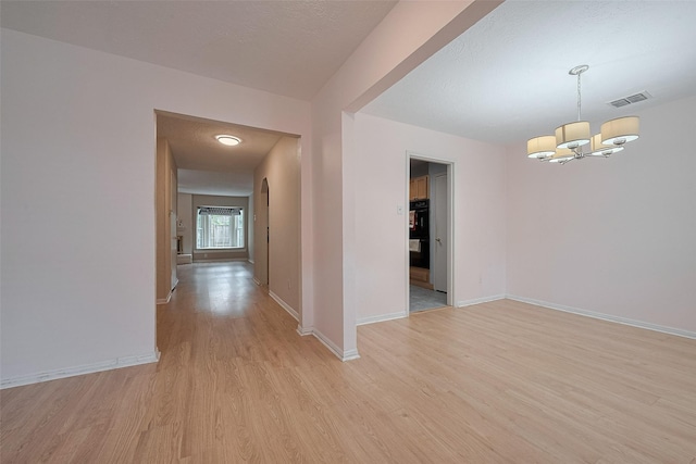 interior space featuring light wood-style floors, baseboards, an inviting chandelier, and visible vents