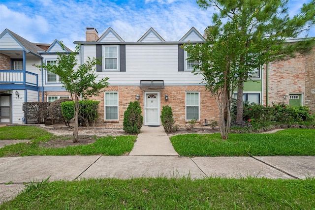 townhome / multi-family property with brick siding and a chimney